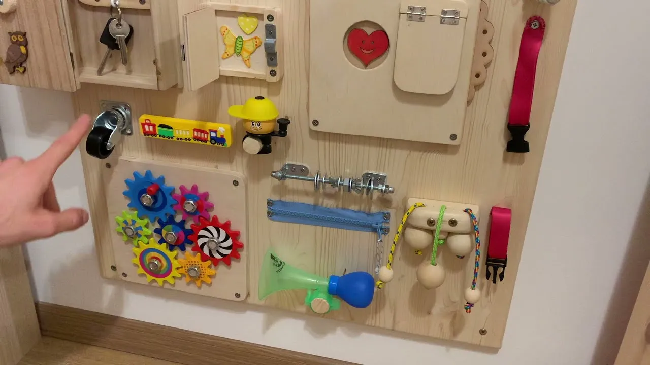 Hand-built wooden busy board with latches, gears and toys mounted on a wall