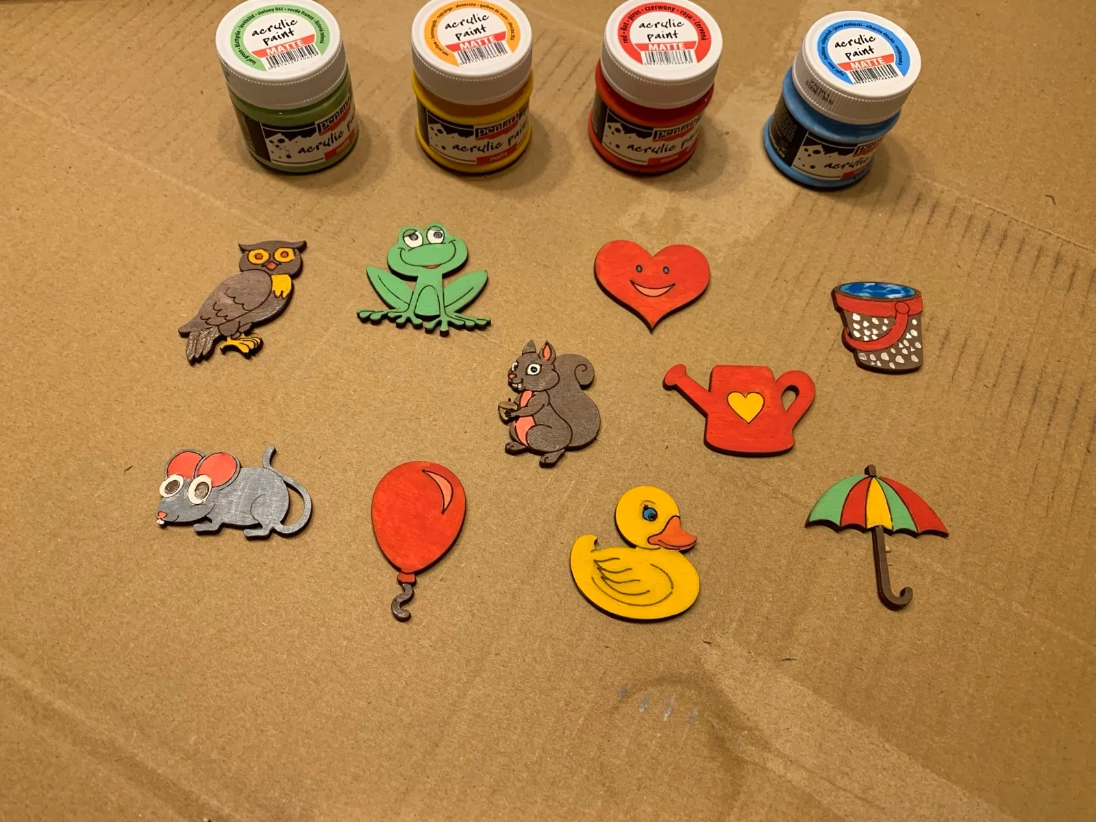 Hand-painted wooden animal figures next to the paint pots