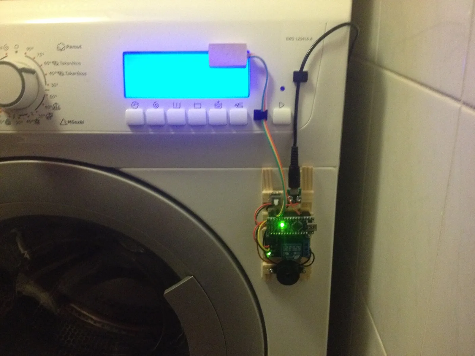 The finished setup on the washing machine: sensor over the screen, control unit on the side