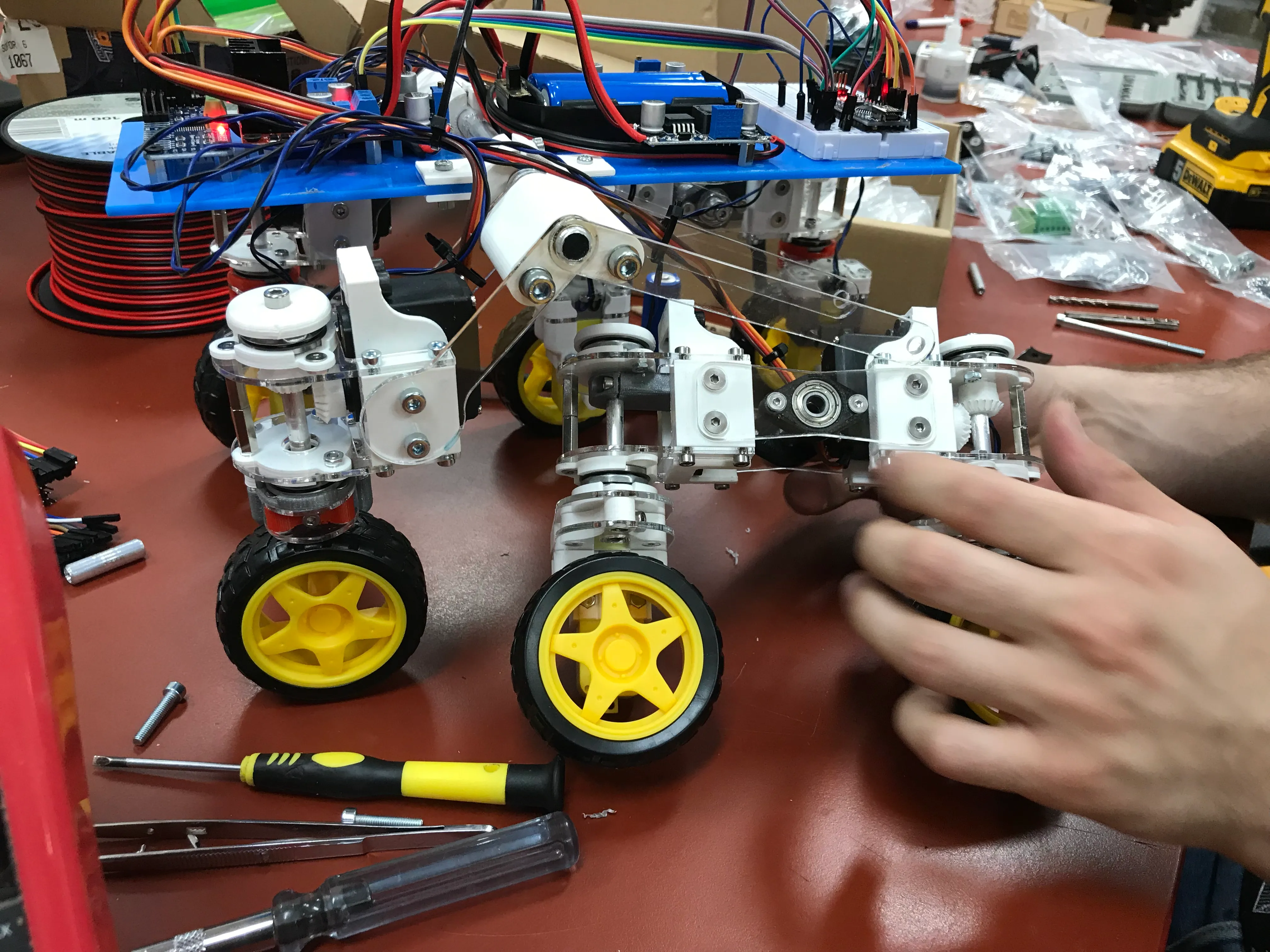 An early prototype on the workbench: laser cut acrylic plates, 3D printed steering parts and breadboard electronics on top