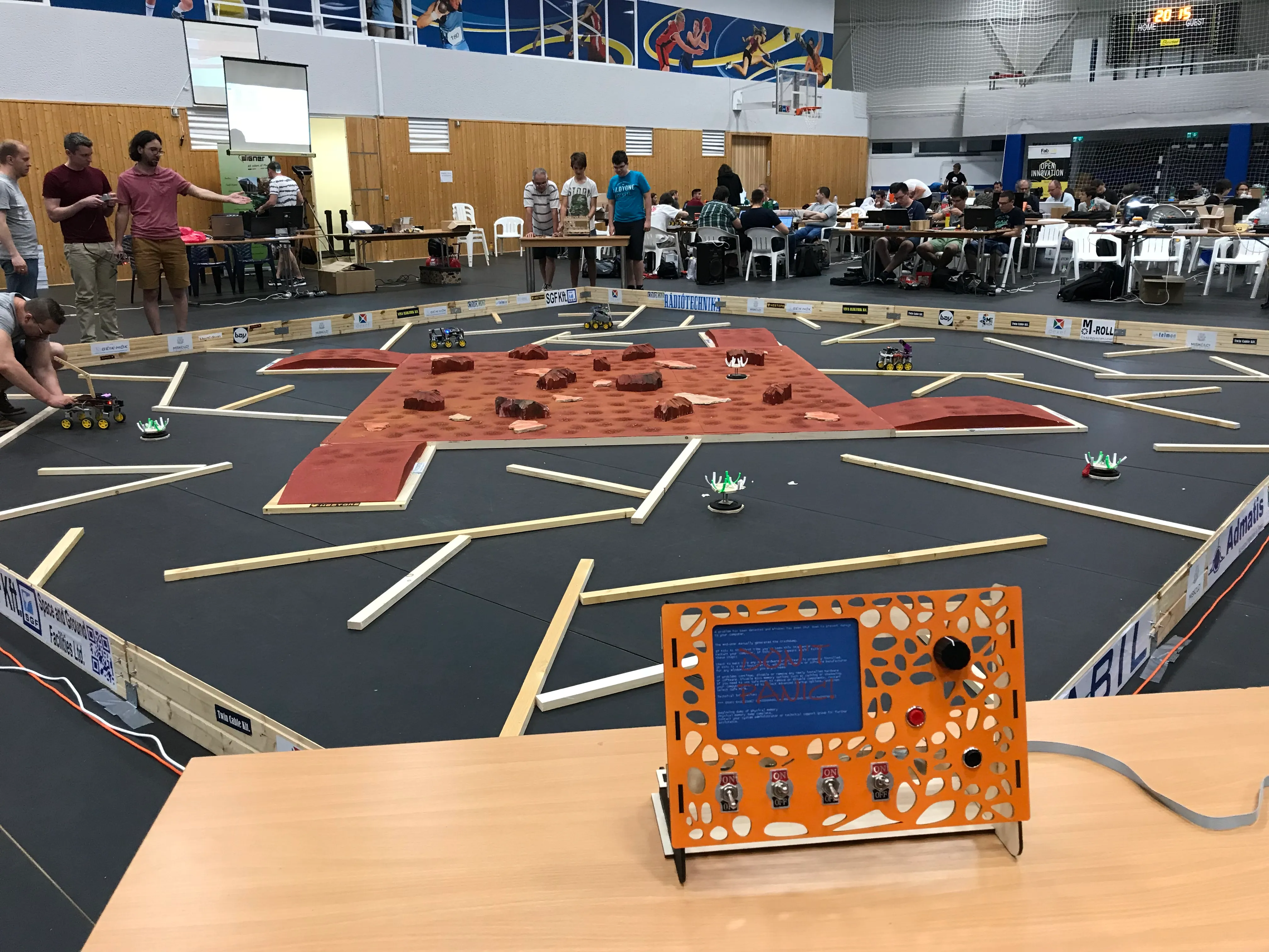 The competition course: red Martian terrain with rocks in the middle, a labyrinth of wooden strips around it and our laser cut control console in the foreground