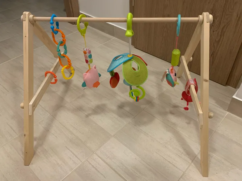 Foldable wooden baby gym that hangs toys within reach to encourage movement and support early development