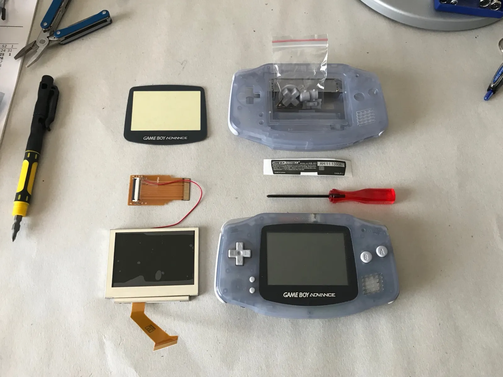 All the parts for the screen mod laid out: new backlit screen, new case, ribbon adapter, screen cover