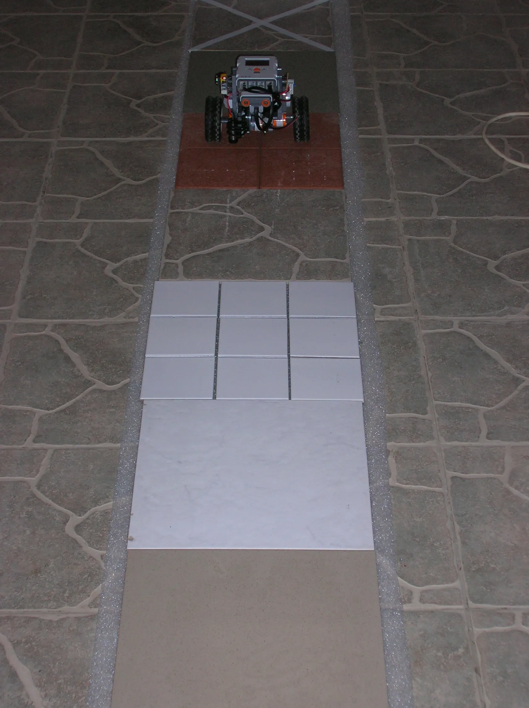 Building material measurement: floor tiles and wall tiles laid in a row above a foam strip, with SURI driving over them and counting the radiation at each one